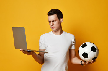 Young man with laptop and a soccer ball