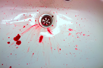White ceramic sink with red blood stains. The concept of bloody suicide and disease
