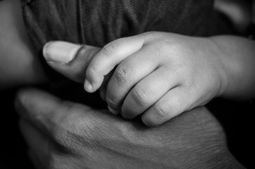 closeup of hand of african baby taking a hand of african man