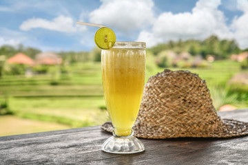 Pineapple juice and straw hat on wooden table