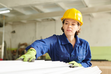 Waist up portrait of adult woman wearing hardhat working at metal production factory, copy space