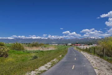 Jordan River Parkway Trail, Redwood Trailhead bordering the Legacy Parkway Trail, panorama views with surrounding trees and silt filled muddy water along the Rocky Mountains, Salt Lake City, Utah. 