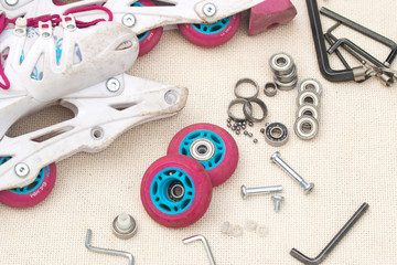 Roller skate bearing replacement. Disassembled roller skates, new and worn bearings, axles, bushings, screws and hex wrenches.