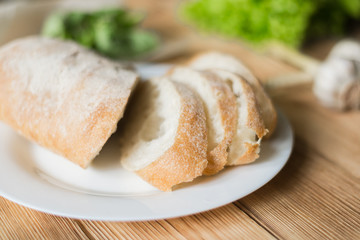 Sliced bread, ciabatta on a white plate. Preparation for the preparation of bruschetta.