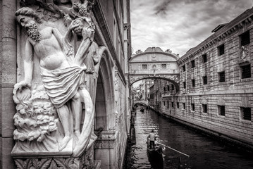 Venice cityscape with old sculpture in black and white, Italy. Tourist gondolas sail under famous...