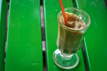 Instant coffe in a glass with a red straw.