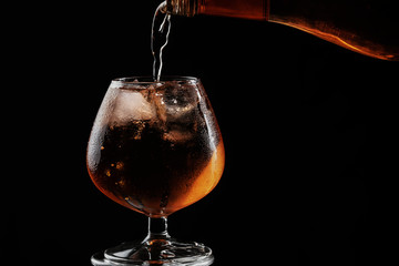 whiskey is poured into a brandy glass with ice, the glass is full and sweated.