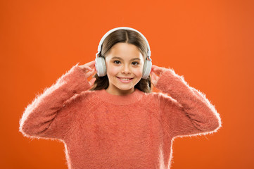 Delivering sound right to her ears with headphones. Small child listening to music in wireless headphones. Little girl wearing modern headphones. Cute kid enjoying stereo sound in headphones