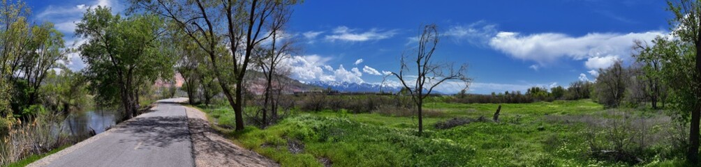 Jordan River Parkway Trail, Redwood Trailhead bordering the Legacy Parkway Trail, panorama views with surrounding trees and silt filled muddy water along the Rocky Mountains, Salt Lake City, Utah. 