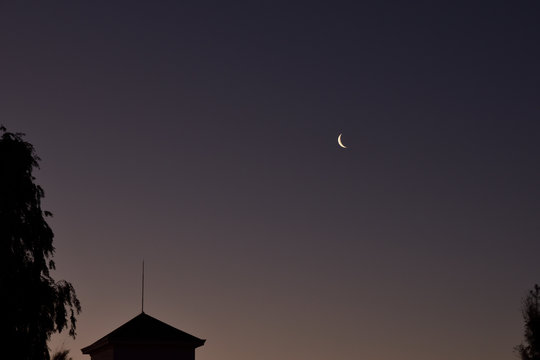 Incipiente luna cuarto creciente sobre los edificios al atardecer