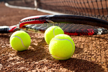 Tennis racket and balls on the clay tennis court. Close up.	