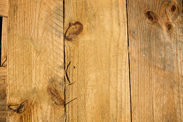 Three rough knotty planks of pine wood lined up side by side in the sunshine.