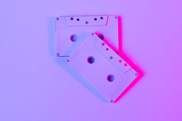 Trendy reviving retro audio cassette tape on pink and green neon light. Analogue music hipster trend. Bright neon colors. Minimal and surreal. style of the 80's Top view