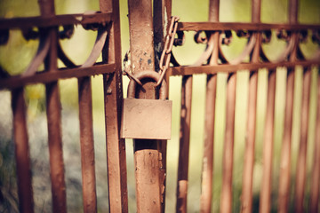 Gate closed on the lock on a rusty chain.