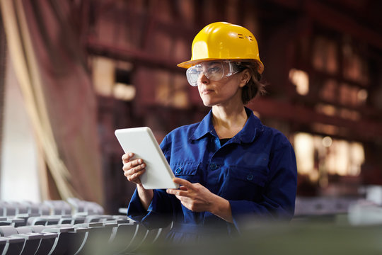 Waist up portrait of female worker using digital tablet while supervising production at plant, copy space