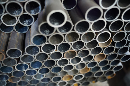 Background image of metal pipes stacked in warehouse of industrial plant, copy space