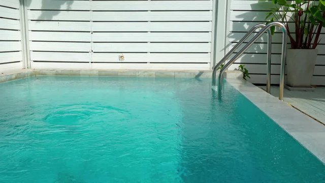Clear blue water of a resort plunge pool behind a bungalow. Private swimming pool with ladder and fence. Perfect vacation at a luxury tropical location.