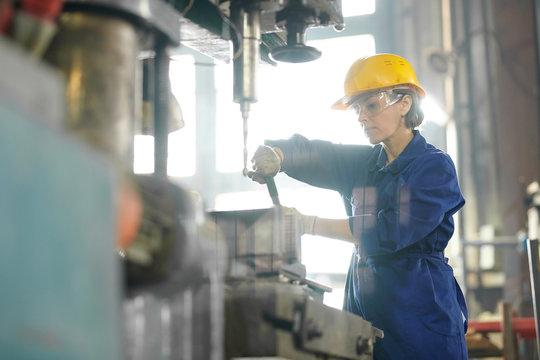 Side view portrait of mature woman working at factory and repairing machine units, copy space