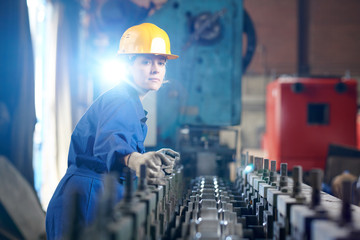 Waist up portrait of beautiful woman working at industril plant standing against bright light, copy...