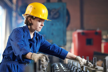 Side view portrait of young woman working at industril plant standing against bright light, copy...