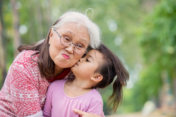 Happy elderly woman kissed by her granddaughter