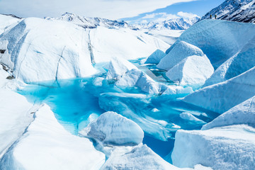 Two trekkers above a frozen glacier lake in Alaska's Chugach Mountains.