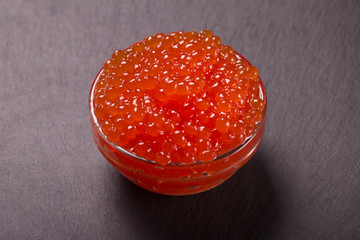 red caviar in glass bowl on black background