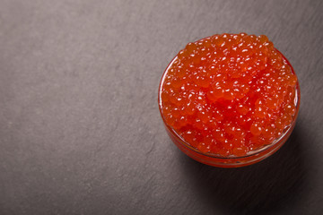red caviar in glass bowl on black background