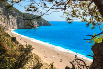 Milos beach in with cyan blue water and rock with blue sky in the background.