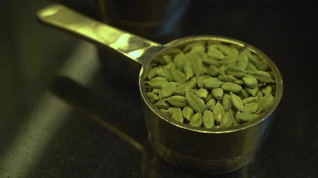 A steady, extreme close up shot of a metal container filled to the top with some green seeds.