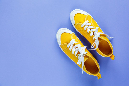 New pairs of yellow  sneakers on violet background with copy space. Lifestyle  sneaker sport shoe. 