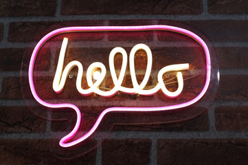 Neon sign background saying " HELLO " Sign hanging on a wall and lit brightly.