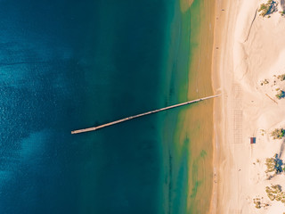 Top view of beach with blue sea and pier, aerial view