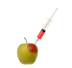 Syringe with colored liquid stuck into an apple isolated on white.