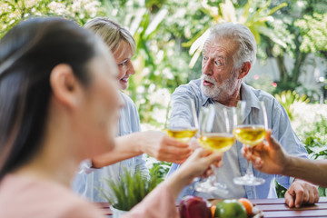 Group of senior enjoy party at home, drinking white wine, sing songs to relax