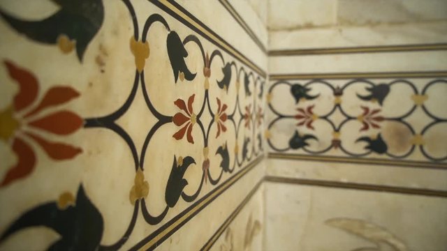 A hand held, extreme close up shot of colorful paintings on white marble.
