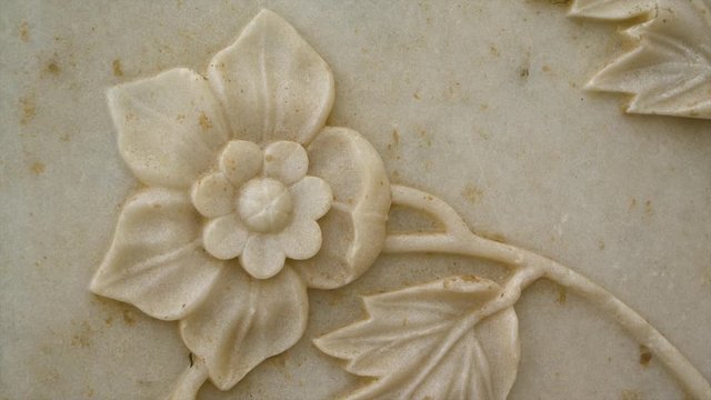 A hand held, extreme close up shot of an old flower decorated wall.