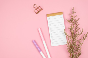 Top view of notebook stationery and flower on pink background