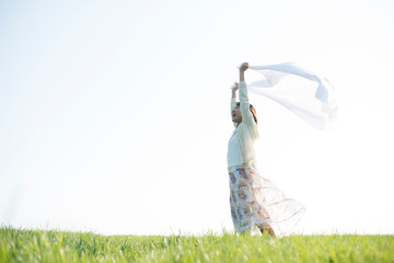 草原で布を持ち微笑む女性