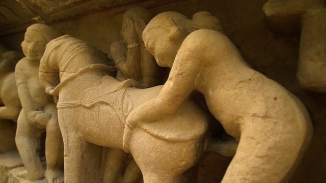 A hand held, extreme close up shot of old stone sculptures on a wall.