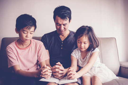 mixed asian children praying with their father at home, family worship online, home church, new normal concept