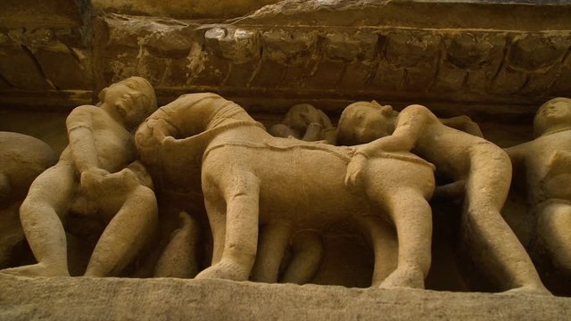 A hand held, high angle, close up shot of a sculpture of men harassing a horse.