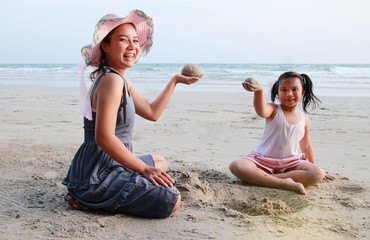 Mother and child are having fun playing sand on the beach