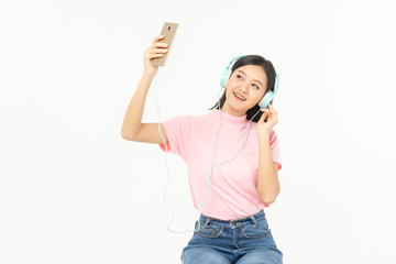 Happy asian teen passenger listening to the music with headphones while holding  mobile phone.businesswoman listening to music with headphones while dancing isolated over white background