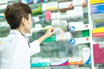 senior Asian pharmacist hand holding medicine box for client or patient in pharmacy drugstore. concept of service, pharmacy drugstore, healthcare,life and people