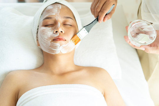 Spa concept. Asian young woman getting facial care or nutrient facial mask by beautician in beauty spa salon,Face peeling mask, spa beauty treatment, skincare.