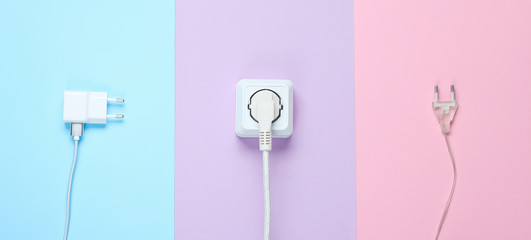 The concept of electrical dependence. Lots of power plugs near power outlets on pastel background