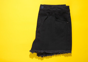 Fashionable women's denim black shorts on yellow background. Top view