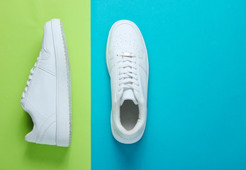 Fashionable white sneakers on a two-tone background. Top view