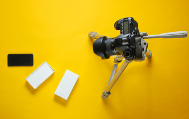 Tehnobloger concept. Unboxing new smartphone with box and review with camera tripod on yellow background. Top view